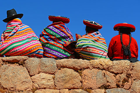 This is a stock photo. A Quechua family sitting on a ledge looking out. 